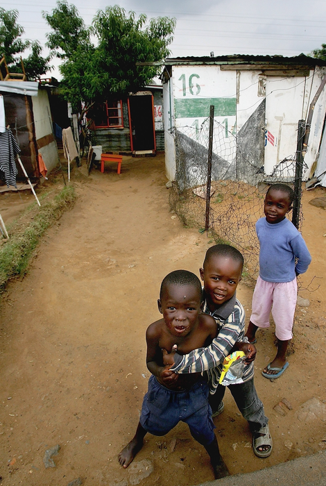 Three young boys look out from their shantytown in Soweto, South Africa, south of Johannesburg.